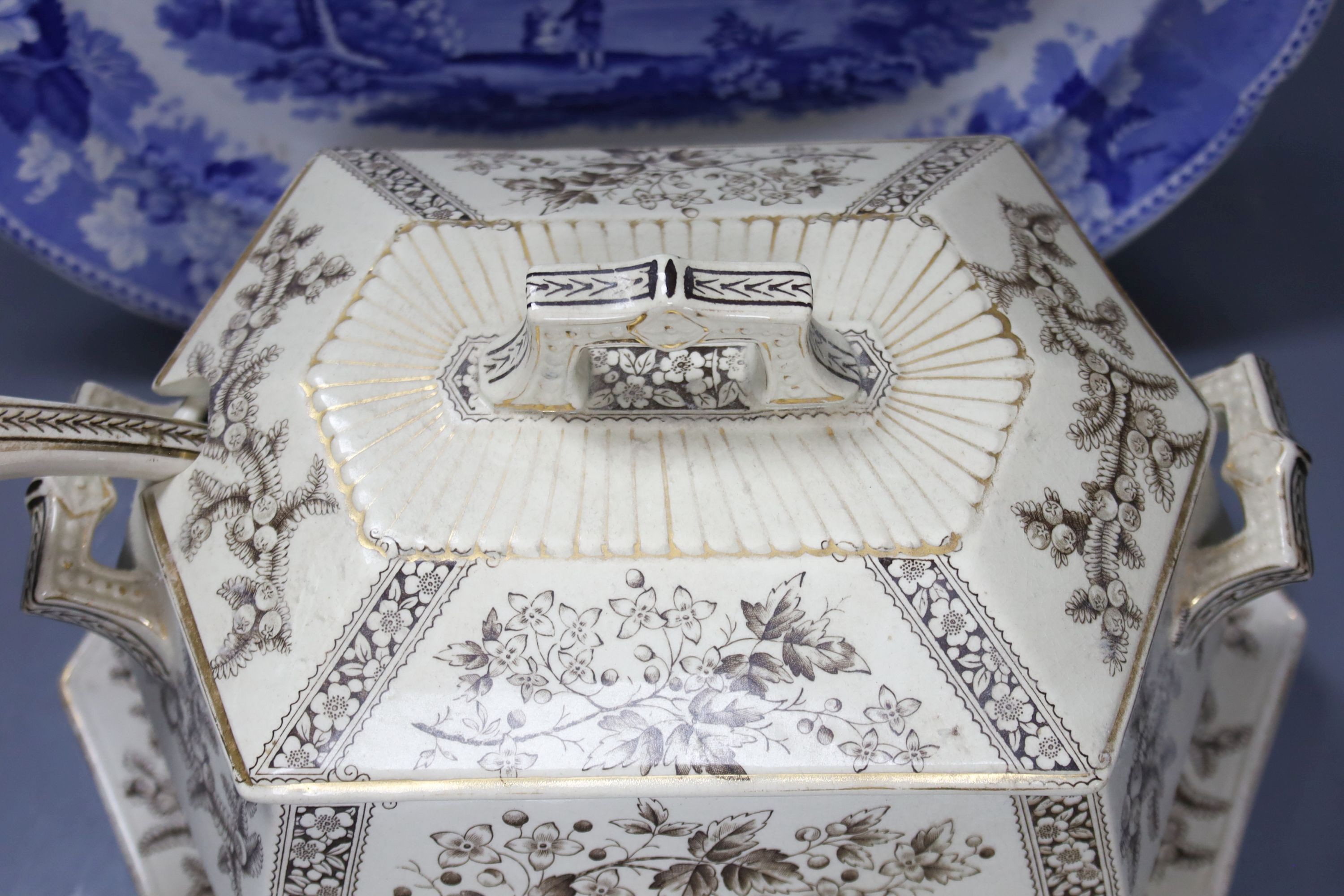 A late 19th century Staffordshire blue and white transfer-printed oval meat dish, ‘The Rokery’, depicting a country house with lake and figures, W 44cm and an octagonal 'Flora' creamware soup tureen with ladle and stand